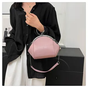 Détail en gros plan d'un sac coquille rose élégant avec bandoulière chaîne tenu par un modèle