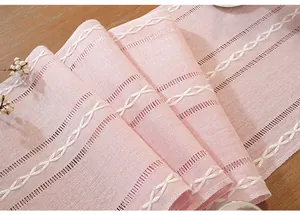 Detailed macro view of pink cotton linen table runner with white embroidery patterns