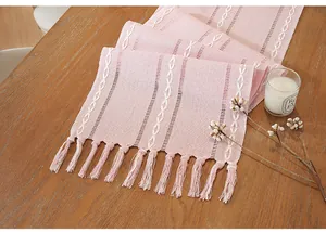 Close-up of pink cotton linen table runner with white embroidery and tassels