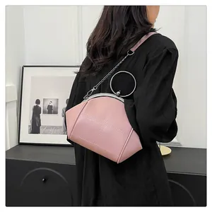 Sac à main rose en forme de coquille avec poignée ronde en métal porté par un mannequin