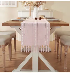 Detail view of pink cotton linen table runner with white embroidery and handmade tassels