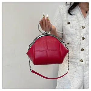 Sac coquille en similicuir rouge tenu par un mannequin avec poignée ronde et chaîne