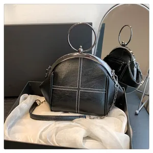Détail du sac coquillage noir avec poignée ronde en métal et coutures blanches