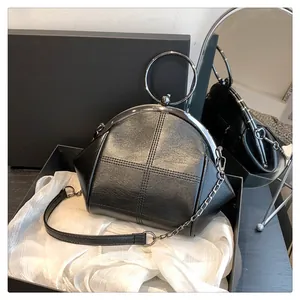 Vue détaillée d'un sac à main noir élégant avec poignée en anneau métallique et chaîne