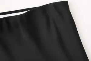 Vista macro detallada que muestra la suave tela de satén negro y la cintura alta de una falda midi