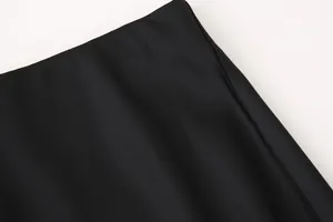 Detalle de la costura de cintura alta y la textura de satén de seda de una falda midi negra
