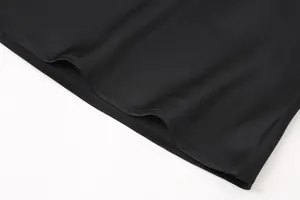 Primer plano del dobladillo de una falda midi de satén negro, tela suave y costuras.