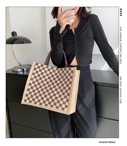 Sac cabas élégant en toile à motif damier tenu par un mannequin en intérieur