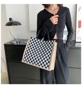 Vue de détail d'un sac cabas en toile à damier noir et blanc porté par un mannequin