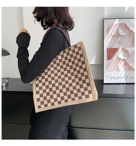 Sac cabas en toile à carreaux porté par une personne dans un intérieur moderne.