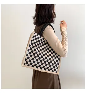 Vue de côté d'un sac cabas en toile à carreaux porté à l'épaule par un mannequin