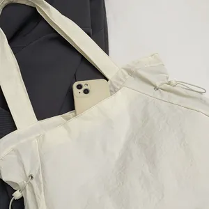 Detailansicht der cremeweißen, wasserdichten Nylon-Tasche mit seitlichem Kordelzug