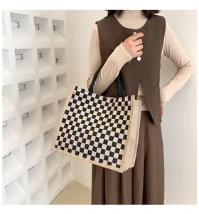 Chic sac fourre-tout en toile à damier noir et blanc porté par un mannequin de mode