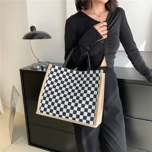 Sac cabas en toile à damier noir et blanc élégant avec bordure beige porté par mannequin