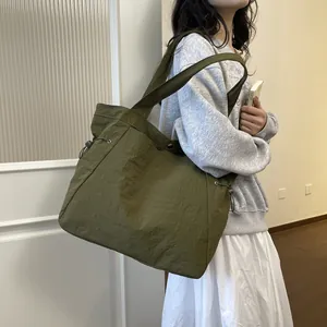 Nahaufnahme einer grünen, wasserdichten Nylon-Tasche mit Knitteroptik am Arm