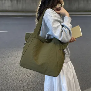 Asiatisches Model trägt eine große armeegrüne wasserdichte Nylon-Einkaufstasche im Freien