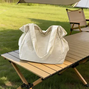 Detailaufnahme einer großen cremeweißen wasserdichten Einkaufstasche auf einem Camping-Tisch