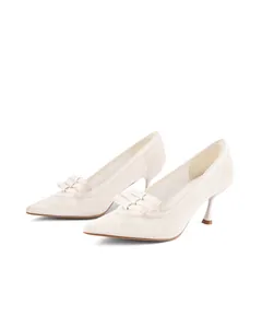 Close-up of elegant white lace pointed-toe high heels featuring a multi-layer bow detail.
