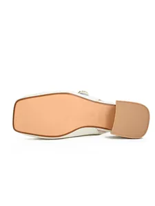 Detail of the textured non-slip sole and block heel of the white square toe sandal