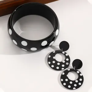 Close-up view of retro black and white polka dot acrylic round earrings and matching bangle set