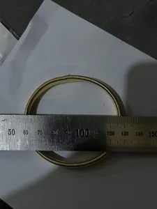 Close-up measurement of a gold metal spring armband showing approximately 75mm diameter