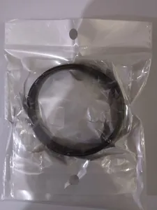 Close-up view of a black metallic spring arm ring inside its transparent plastic packaging