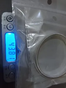 Detail view showing the 43.8g weight of a men's metal spring sleeve garter on a scale