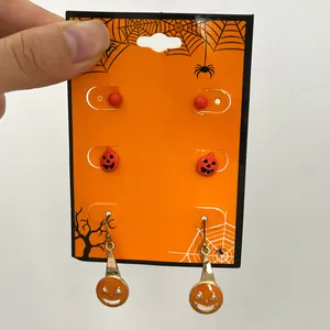 Detailed view of Halloween pumpkin stud and dangle earring set on orange thematic display card