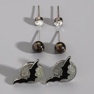 Detailed close-up of a Halloween earring set featuring glittery bat over moon studs