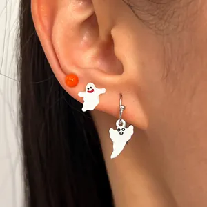Close-up detail of cute white ghost drop and stud earrings worn on ear for Halloween