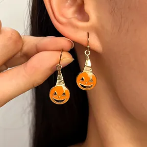 Close-up of orange Jack-o'-lantern pumpkin earrings with gold-tone finish for Halloween