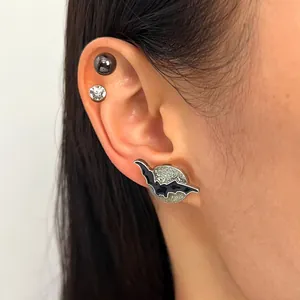 Gothic Halloween bat and glittery moon stud earring worn on a female model's ear lobe