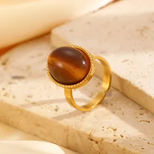 Close-up detail of golden stainless steel ring featuring an oval tiger eye stone inlay