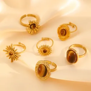 Detailed view of six vintage stainless steel rings with tiger's eye stones on silk fabric