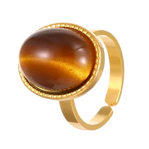 Gros plan d'une bague en acier inoxydable doré avec une pierre œil de tigre polie.