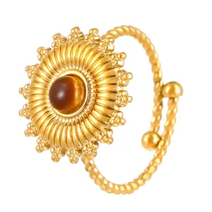 Detail of golden stainless steel ring with central tiger eye stone in sunburst design
