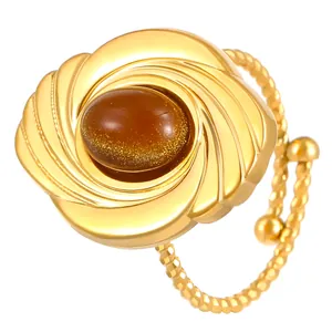 Close-up of a sculptural gold-plated ring with a shimmering brown oval stone.