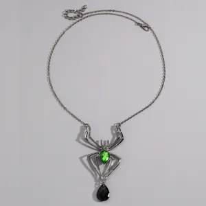 Vue détaillée d'un collier araignée gothique avec des pierres précieuses vertes et noires.