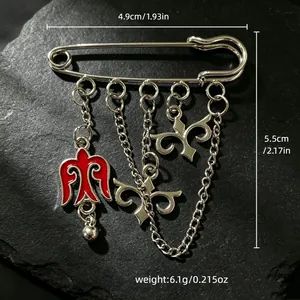 Detalle de un broche de estilo kazajo con un pájaro rojo y amuletos tribales sobre piedra.