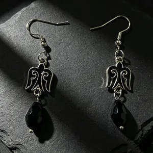 Primer plano de pendientes de estilo kazajo con esmalte negro y cuentas de gota facetadas