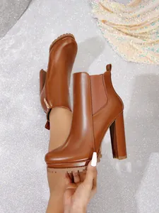 Close-up of brown chunky heel Chelsea boots with lug sole on glittery background