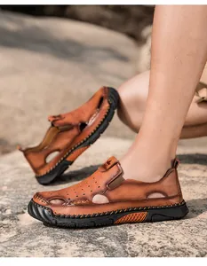 Detailweergave van bruine leren herensandalen aan de voeten in een rotsachtige omgeving.