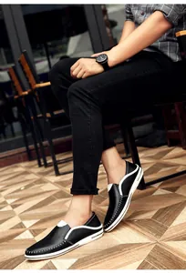 Handgestikte heren loafers van zwart leer met witte bies in een lifestyle setting