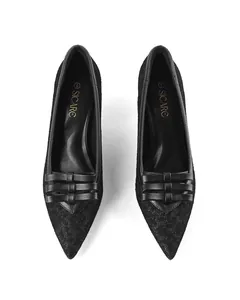 Top-down view of elegant black pointed-toe high heels with bow detail and lace texture