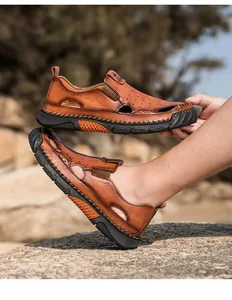 Detailopname van bruine lederen herenzomersandalen met zachte zool en uitgesneden motief