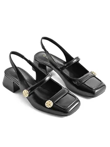 Close-up of black glossy square-toe slingback sandals with gold-tone buckle details.
