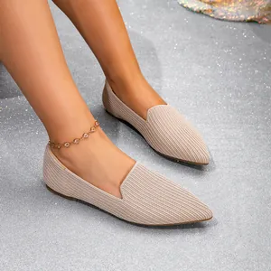 Close-up of beige pointed-toe fly-woven flats on a model against a glittery background.