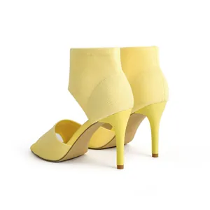 Detailed view of fashionable yellow knitted open-toe high-heel sandals with sleek stiletto