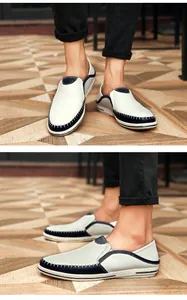 Detailweergave van handgenaaide lederen loafers voor heren in wit en marineblauw.