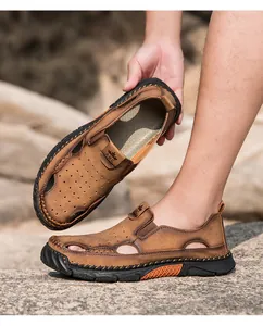 Detailopname van ademende bruine leren herensandalen met decoratief gatenpatroon